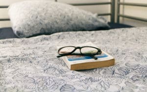 book and glasses on bed